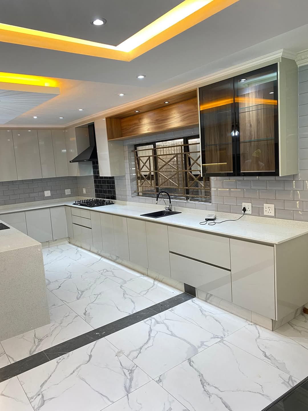 White built-in kitchen with a glowing yellow LED ceiling and timber feature shelf