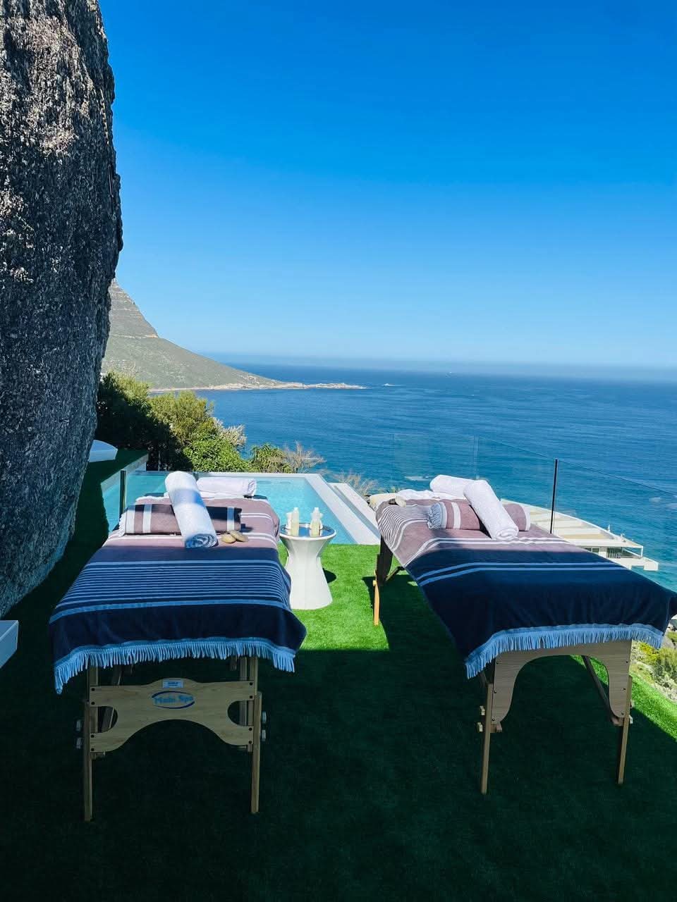 Hiking trails and outdoor massage beds set up overlooking ocean and mountain cliff in Cape Town
