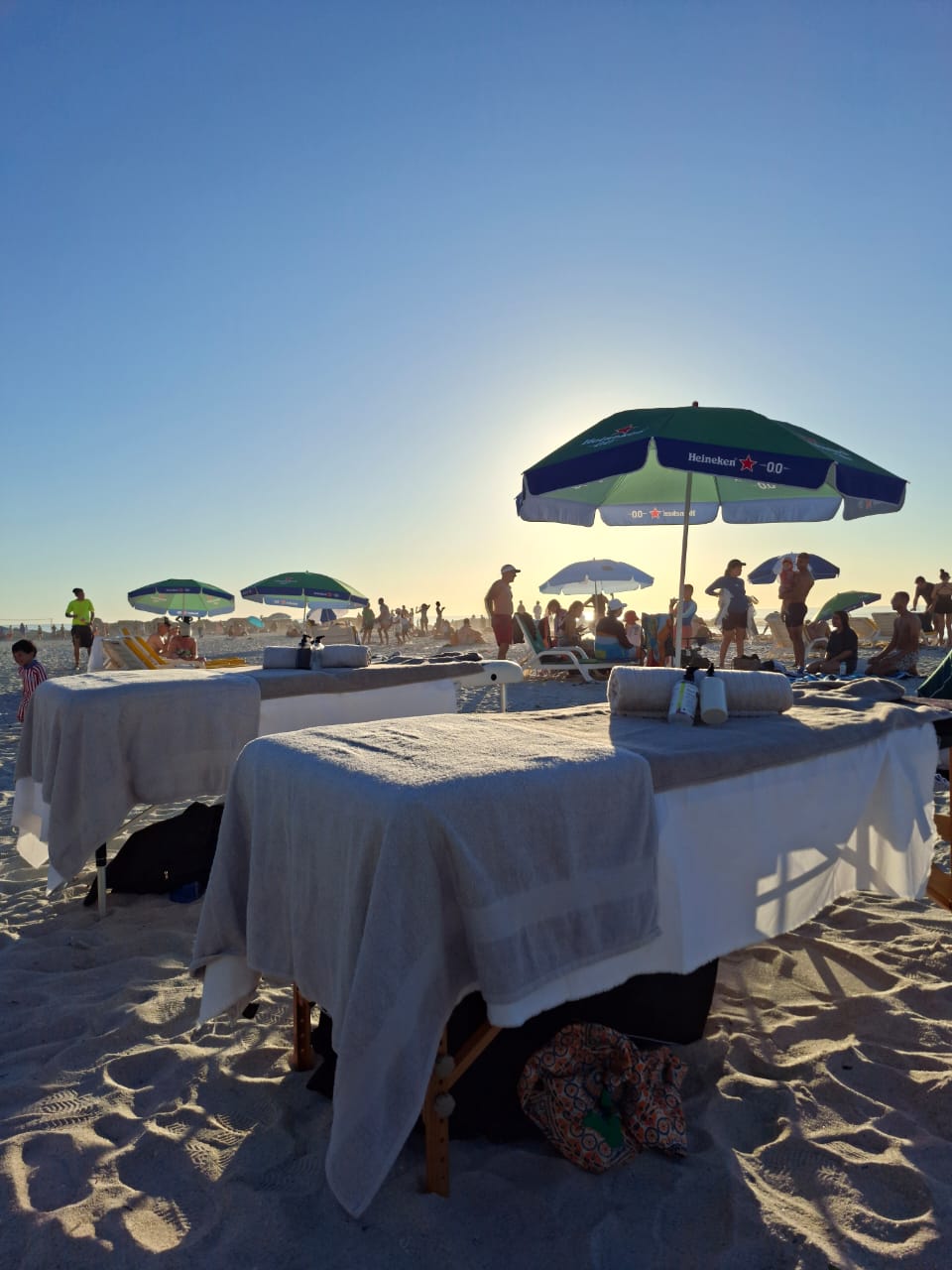 Beach massage setup under umbrella at Camps Bay golden hour