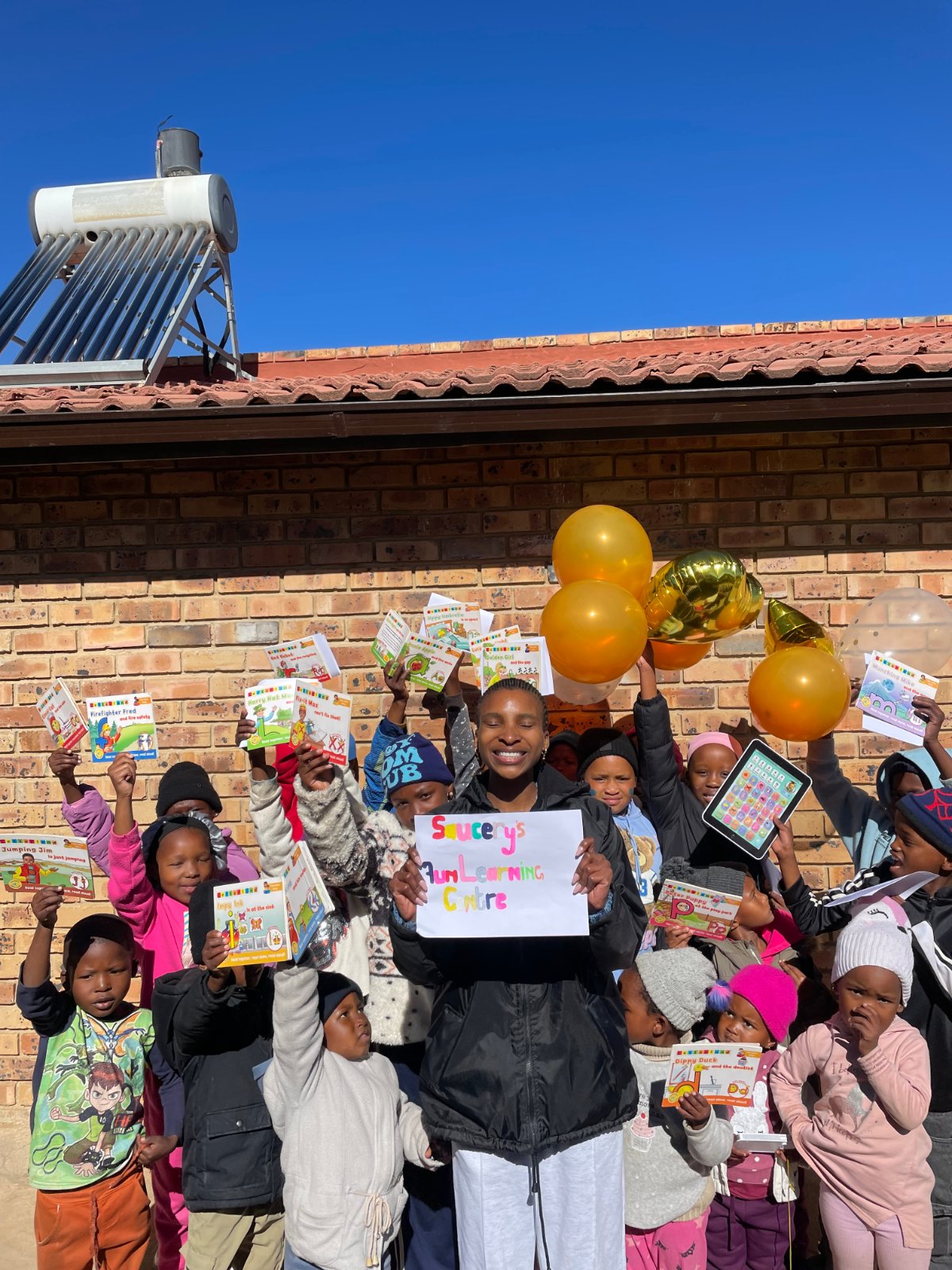 Thandiswa with children holding up books and balloons at Saucery's Fun Learning Centre