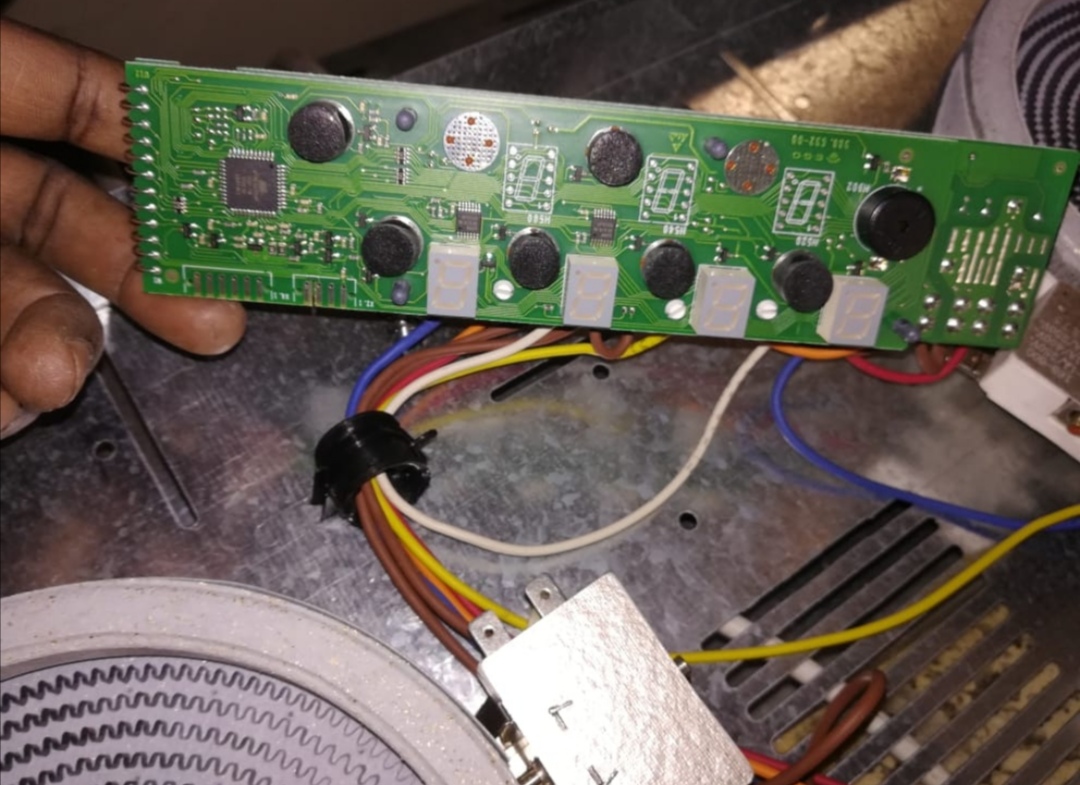 Technician holding a green control board with buttons and displays