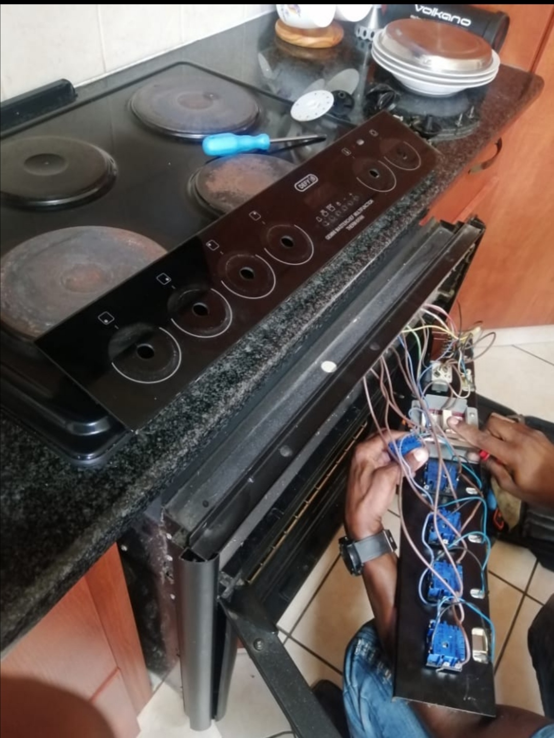 Technician wiring the control panel of a black electric stove