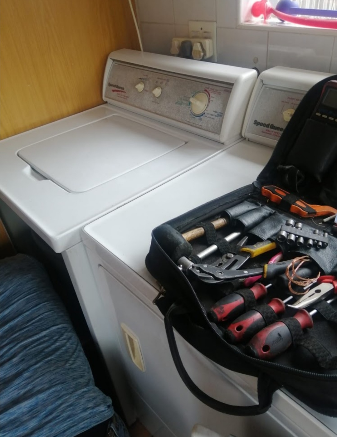 Washing machine and dryer beside an open tool bag full of tools