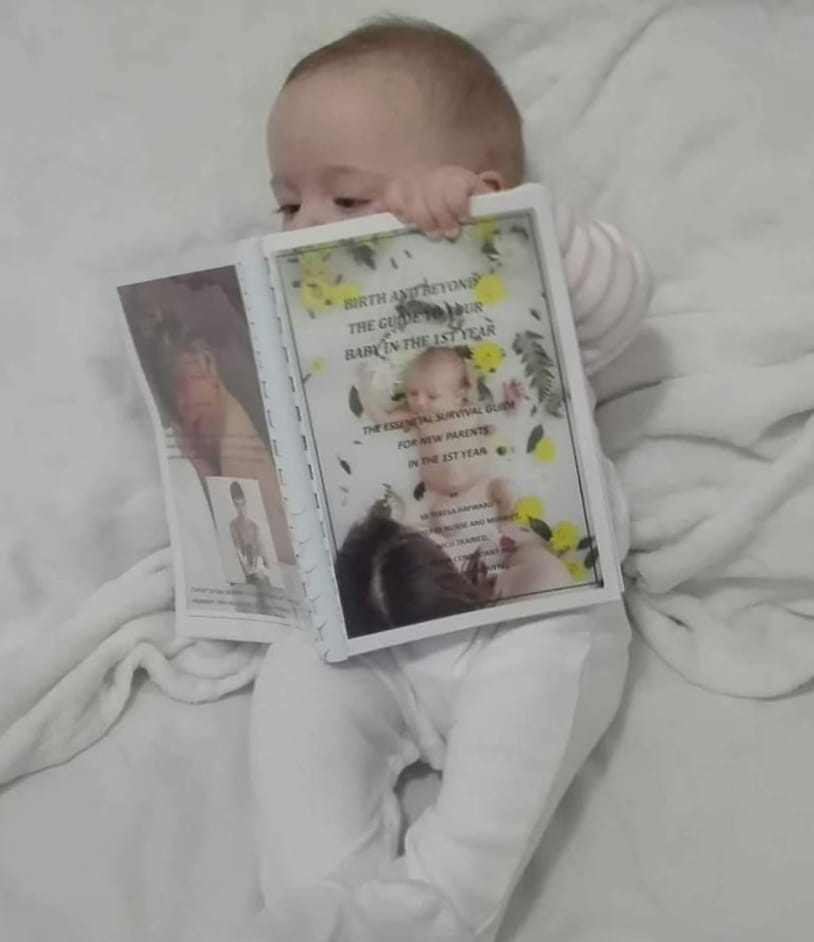 Baby reading Birth and Beyond book