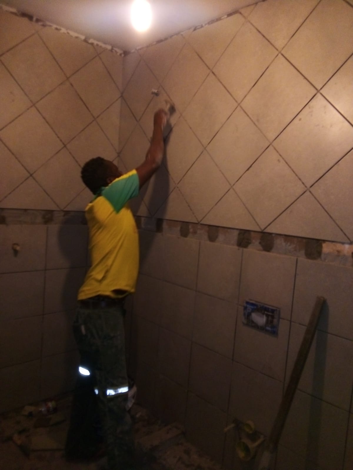Worker installing wall tiles in a bathroom