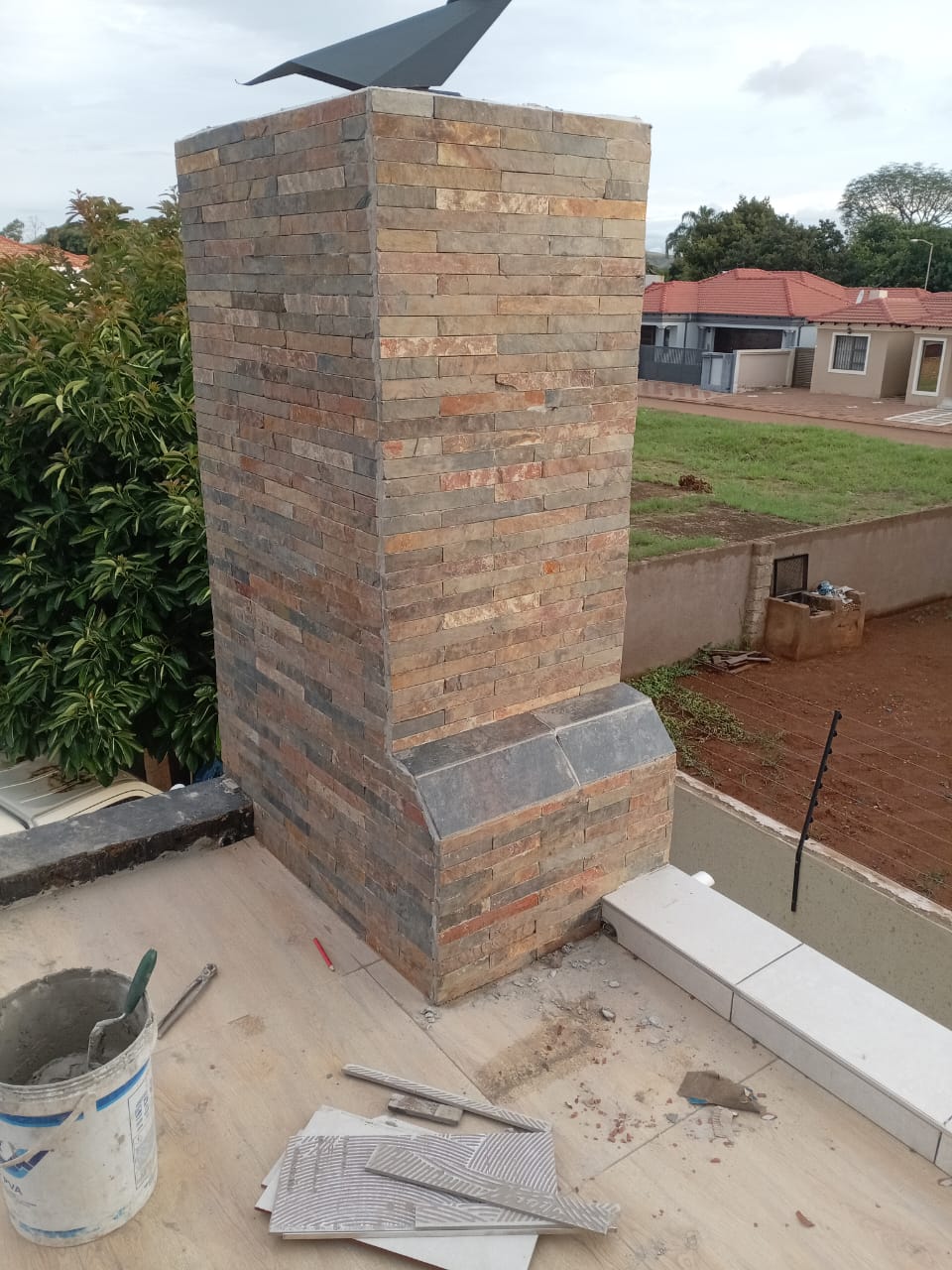 Newly built stone-clad chimney on a roof