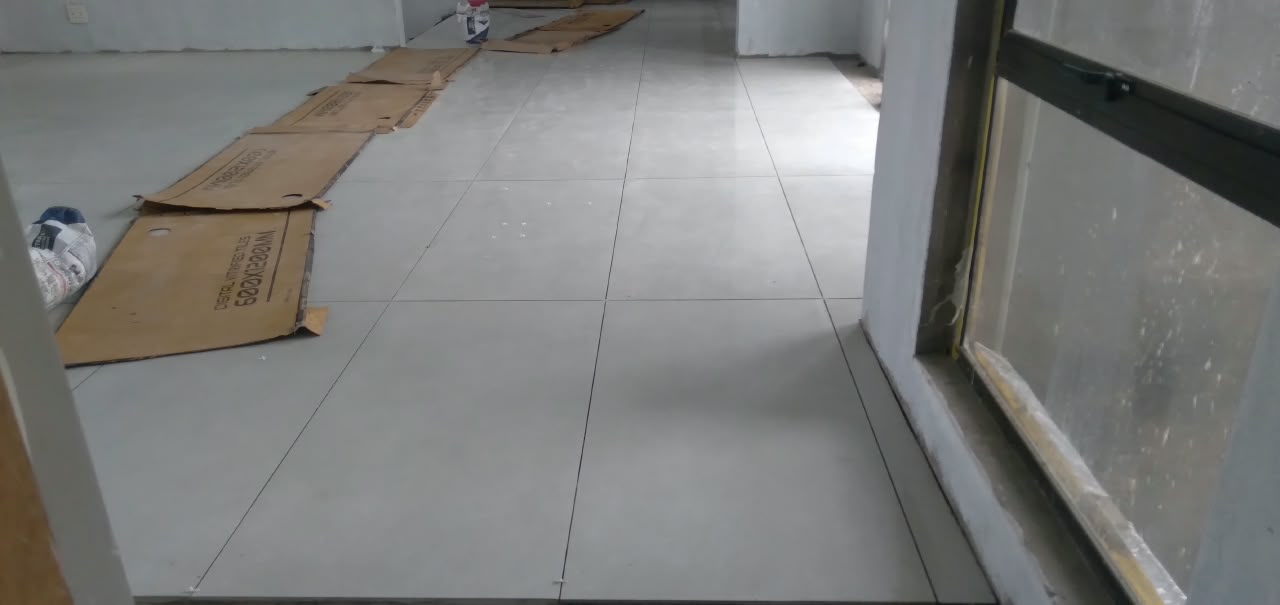 Large light-grey floor tiles with straight, tidy joints in a room with a window