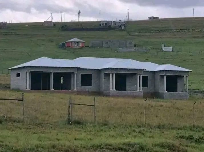 Block house with a silver roof under construction on a hillside, by Mundende Building Construction and Carpentry