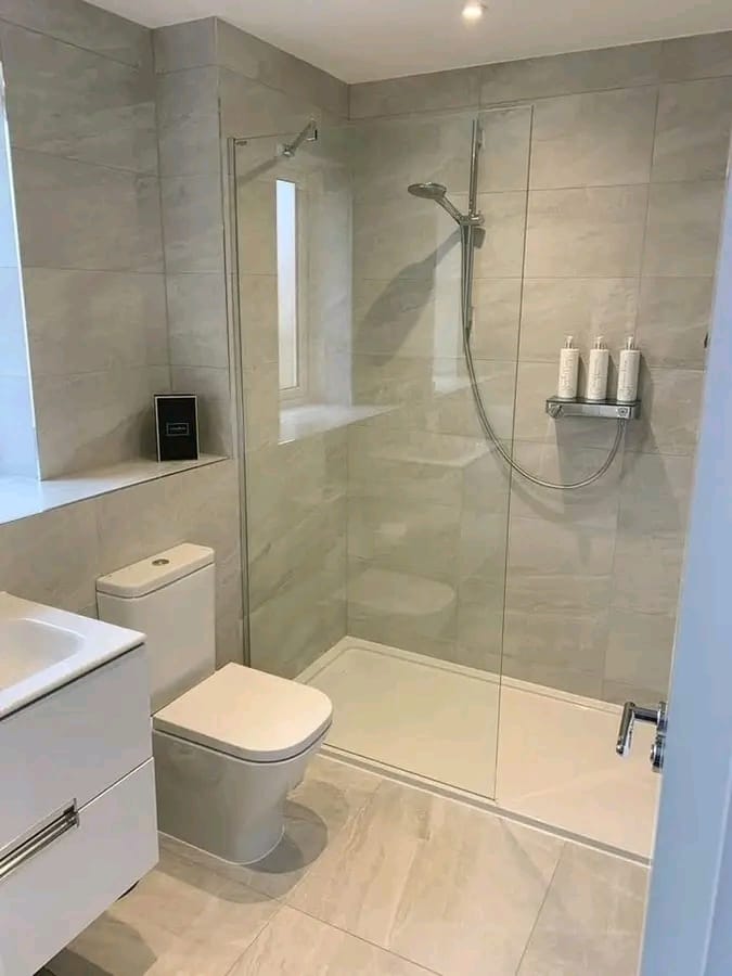 Bathroom with a walk-in shower, tiled walls and a wall-hung vanity, by Mundende Building Construction and Carpentry