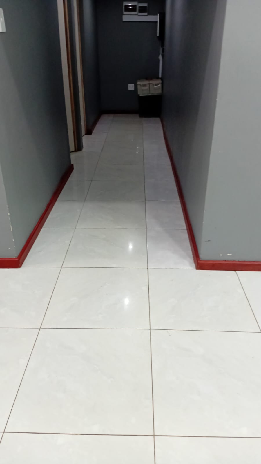 Tiled passage with grey walls and red skirting, by Mundende Building Construction and Carpentry
