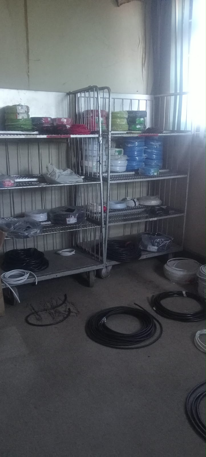 Metal shelves holding coloured and black cable rolls in the store