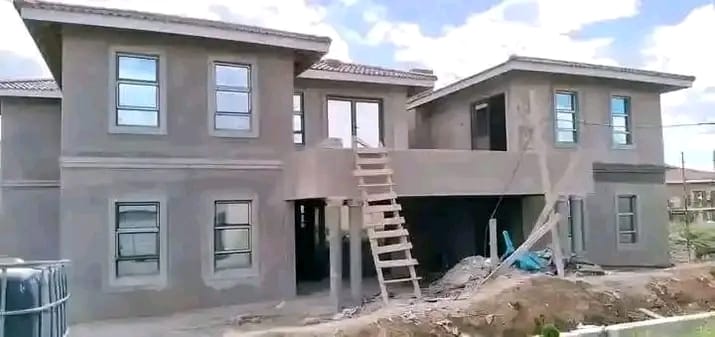 Rendered double-storey house under construction with an external timber ladder, by Mundende Building Construction and Carpentry